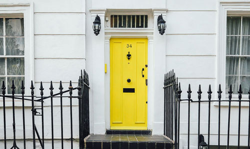 Yellow door on a street with door handles and locks from Kwikset